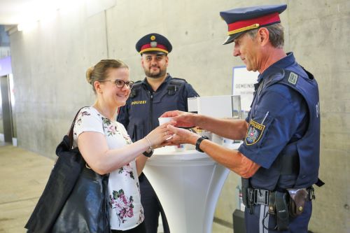 Zwei Polizisten überreichen einer Passantin einen Kaffee bei der Aktion 'Coffee with Cops'
