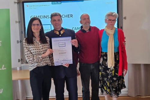 Kerstin Hoi, Geschäftsführerin von CAMPHILL Liebenfels, und Oberst Wolfgang Gabrutsch, GESI-Landeskoordinator, mit Assistenznehmenden bei der Präsentation der unterfertigten Sicherheitspartnerschaftsurkunde.